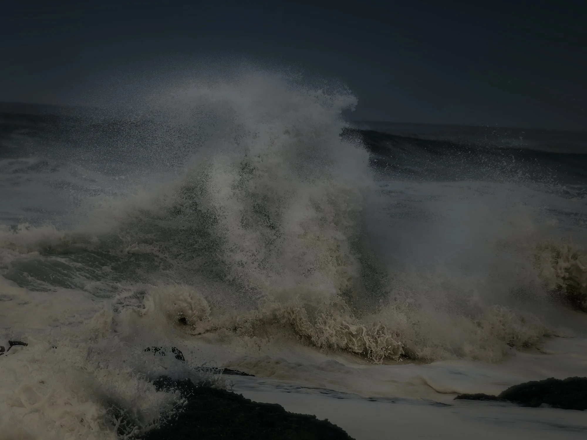 Large ocean wave crashing and splashing with white foam during storm or rough sea conditions.