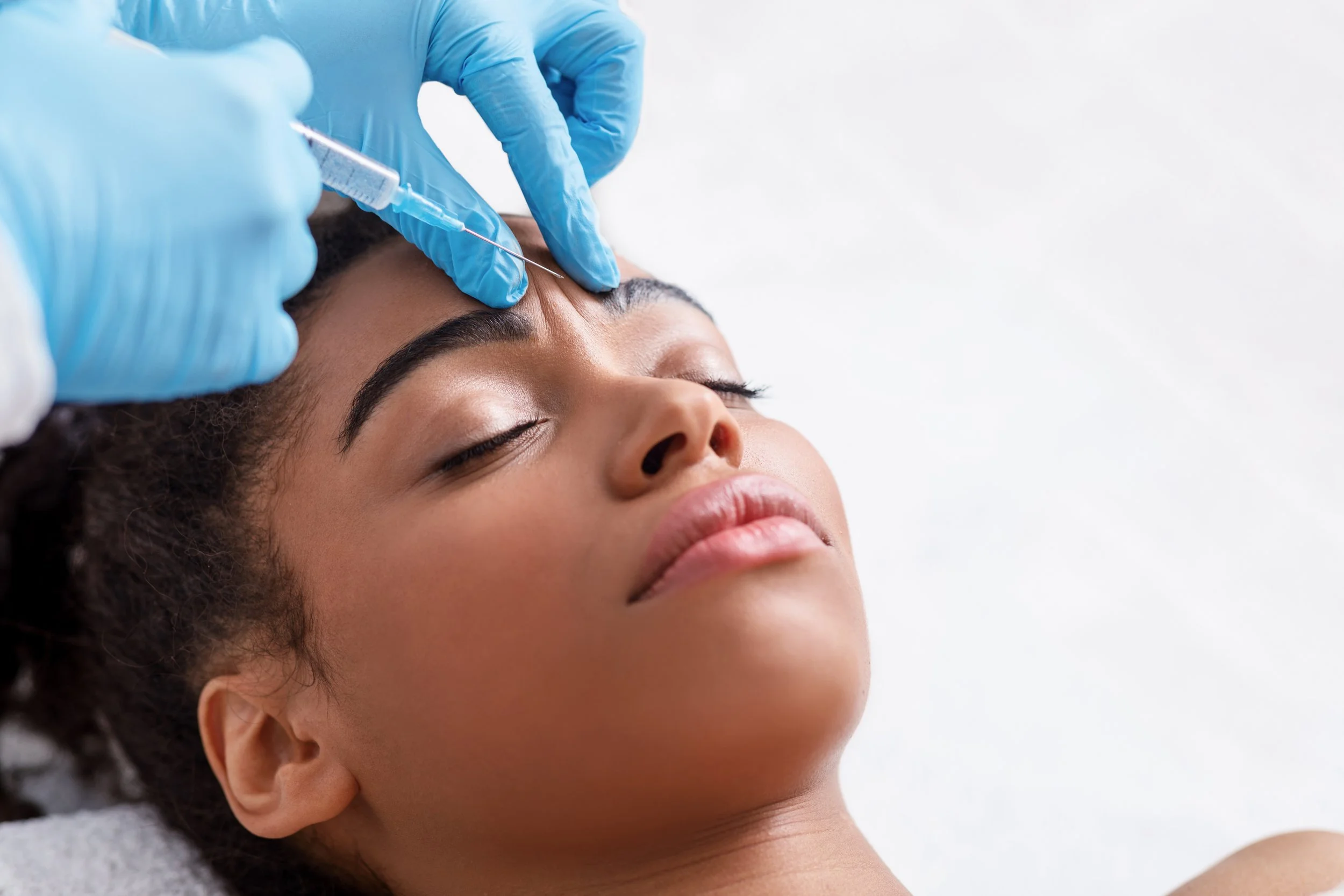 Black woman receiving Botox in between eyebrows