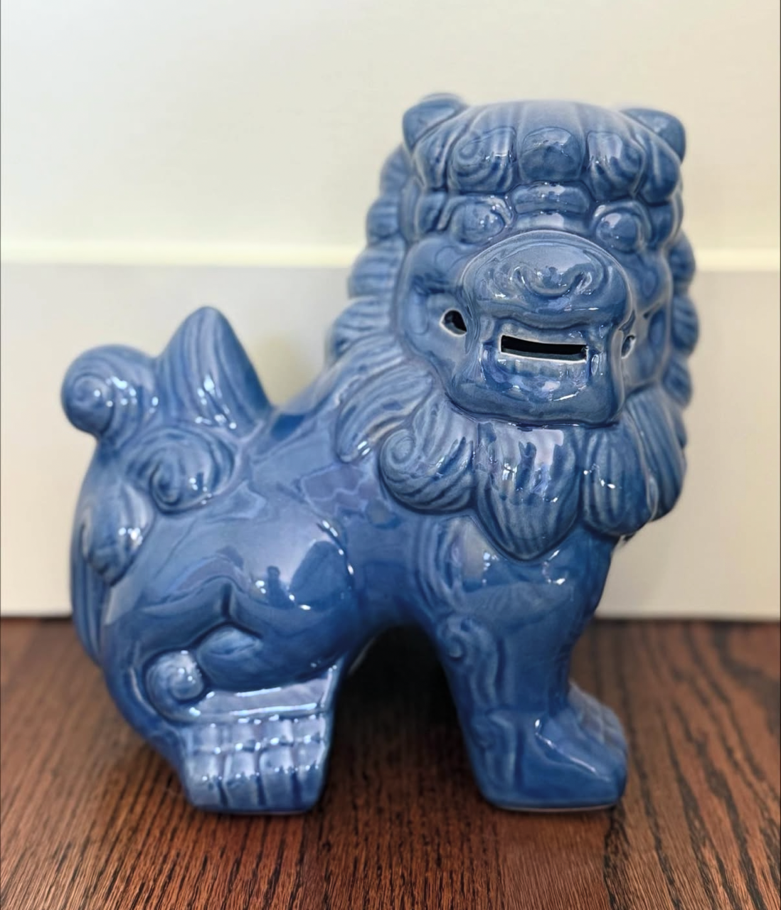 Blue ceramic lion-shaped coin bank on a wooden surface.