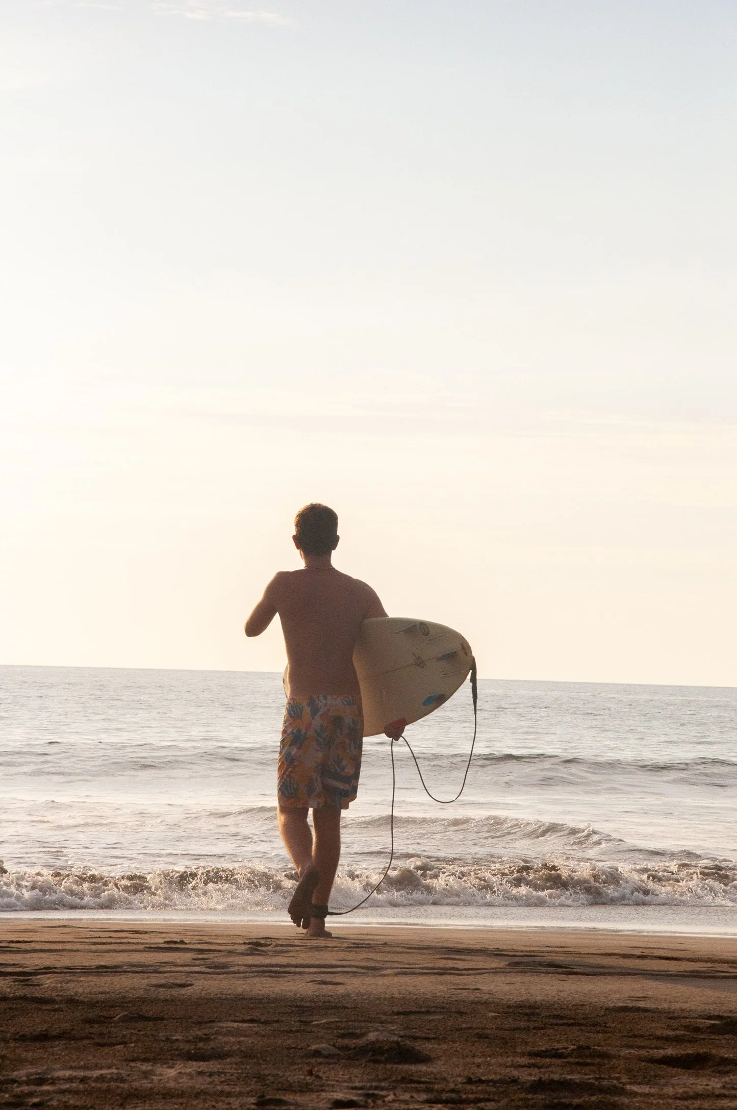 A person surfing on a wave in the ocean with a blue sky background.