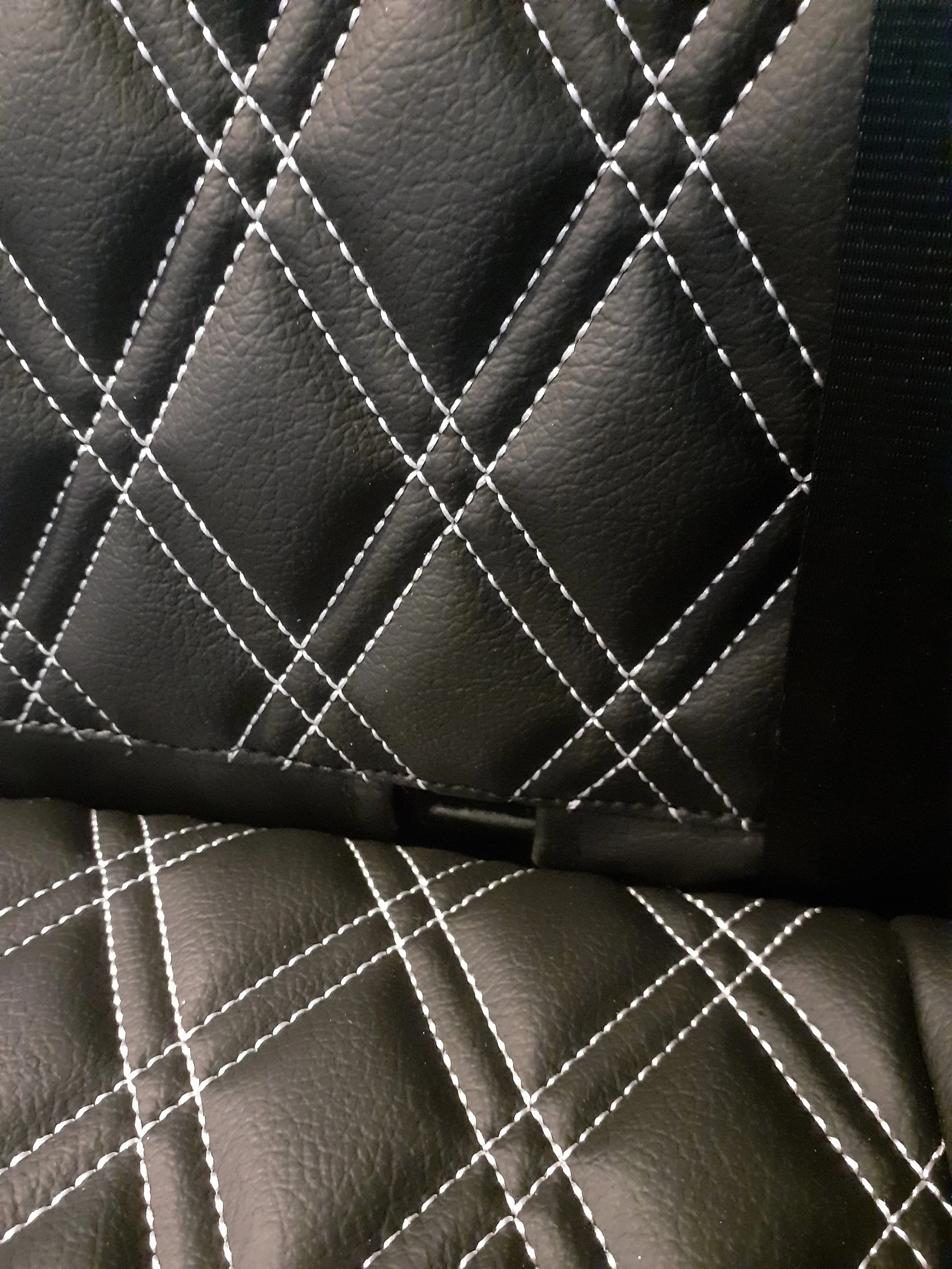 Close-up view of black quilted leather material with diamond pattern stitching in white thread.