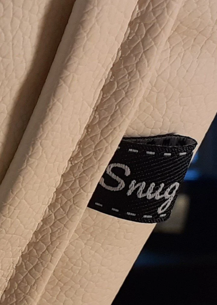 Close-up of a light-colored textured fabric with a black label that reads 'Snug'.