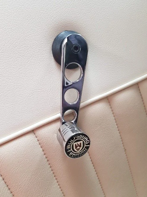A metal clocking-in tool with a Wolfsburg Edition badge hanging on a wall.
