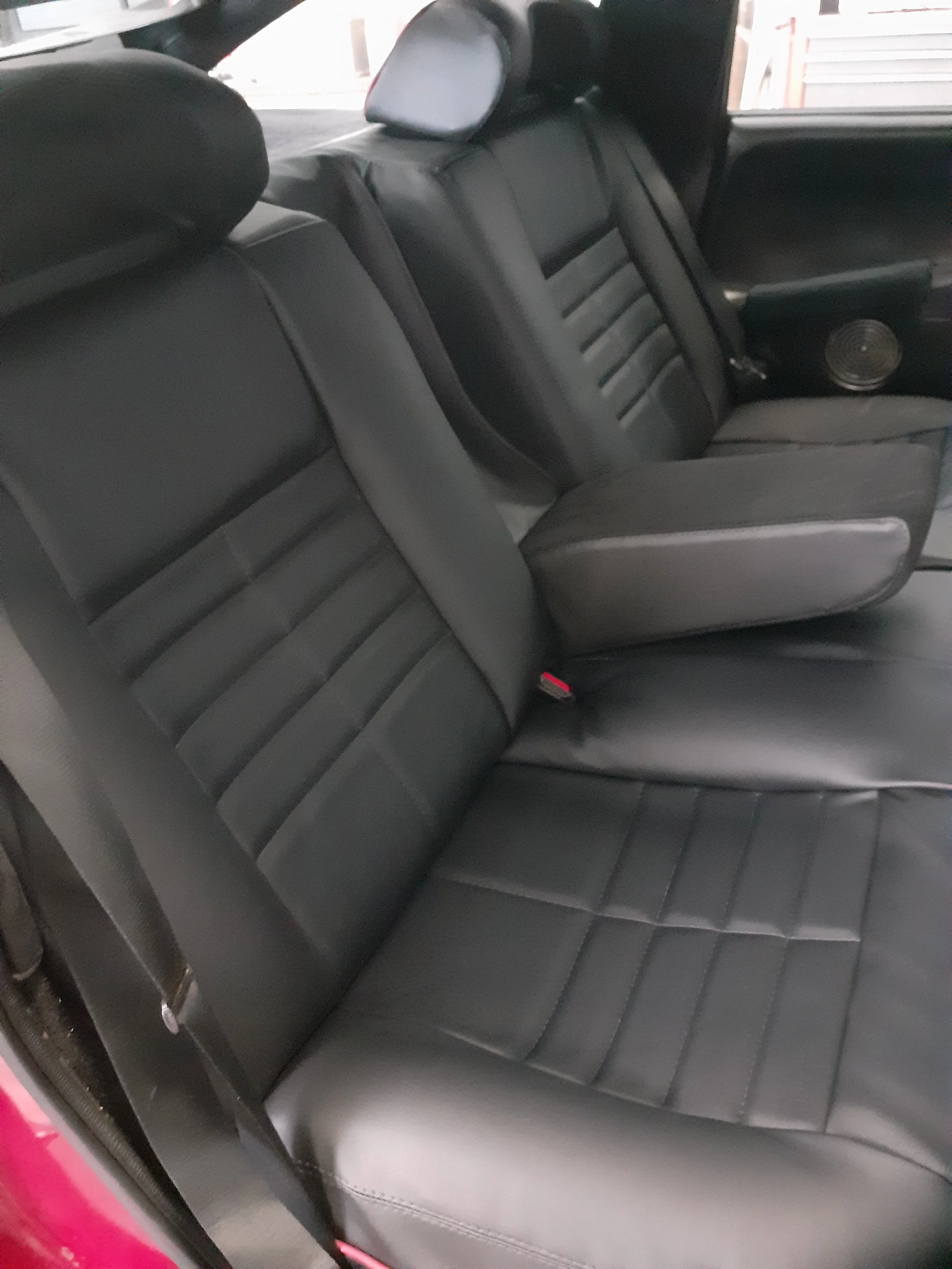 Back seat of a car with black leather upholstery and a headrest.