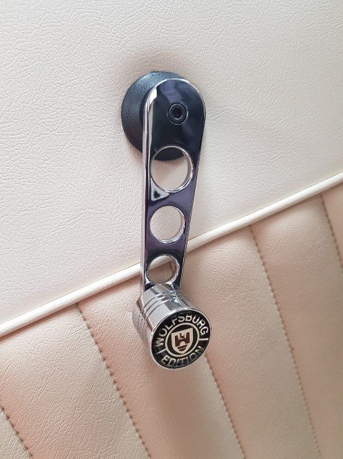 A metal latch lock on a door with a Wolfsburg Edition badge.