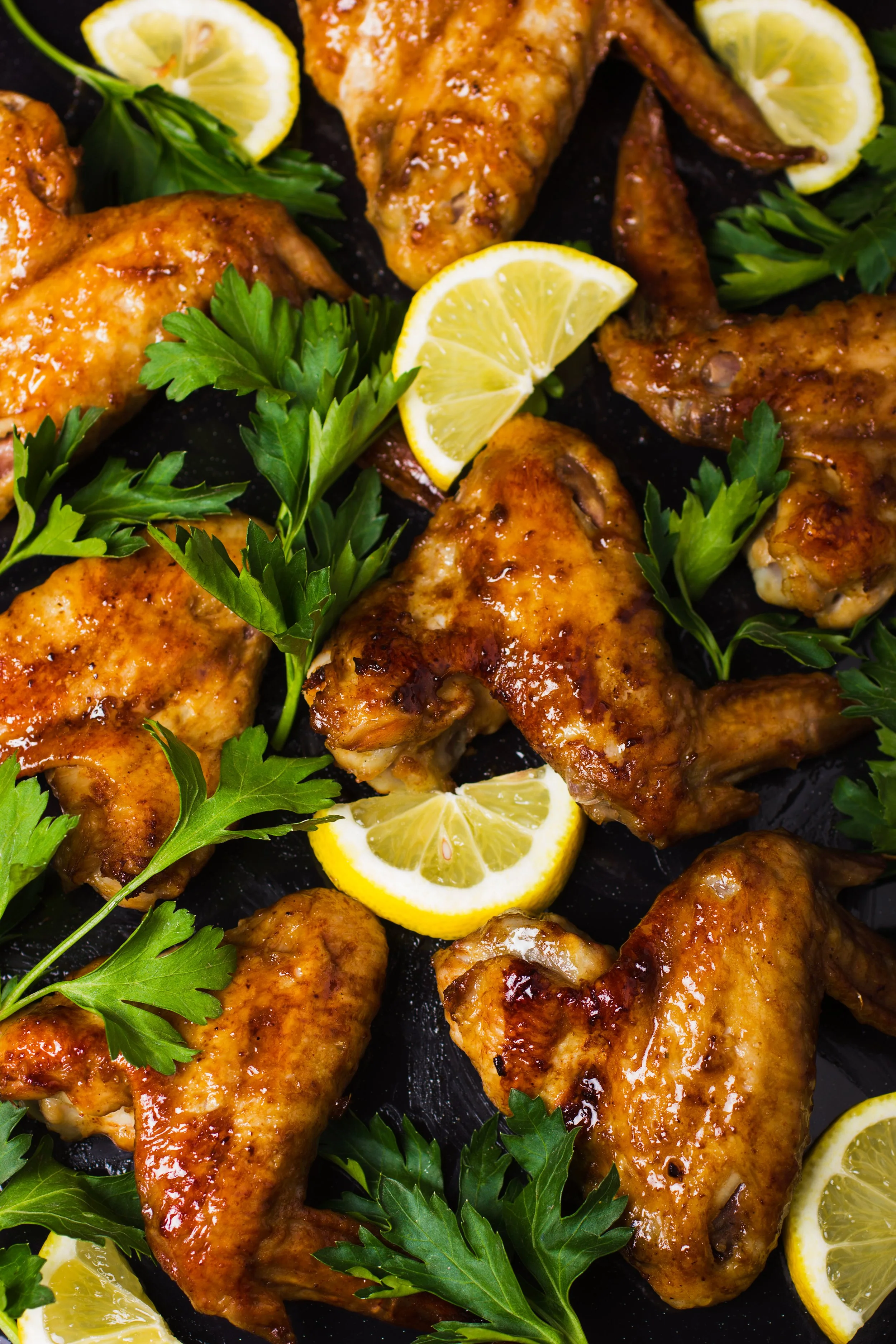 Grilled chicken drumsticks garnished with lemon wedges and fresh parsley.