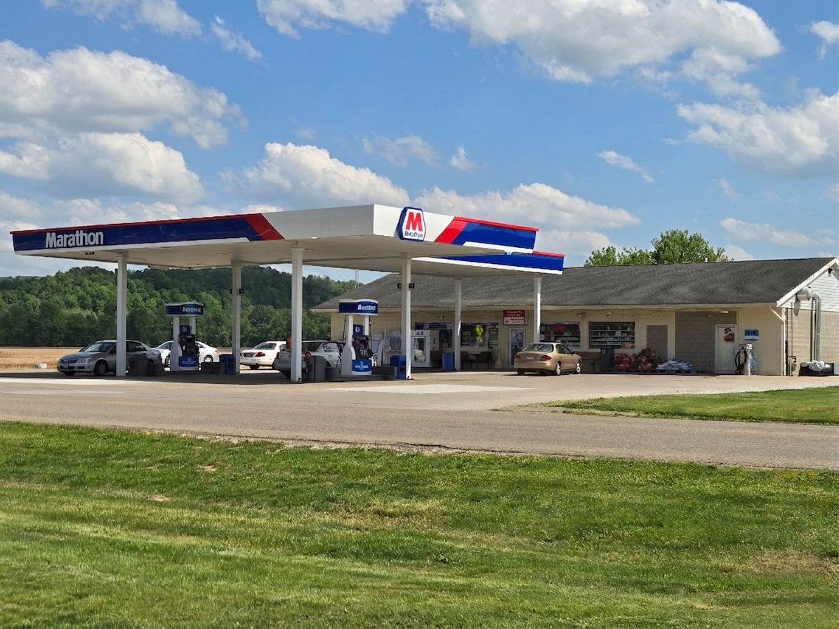A Marathon gas station with multiple fuel pumps and a convenience store on a sunny day with a partly cloudy sky.