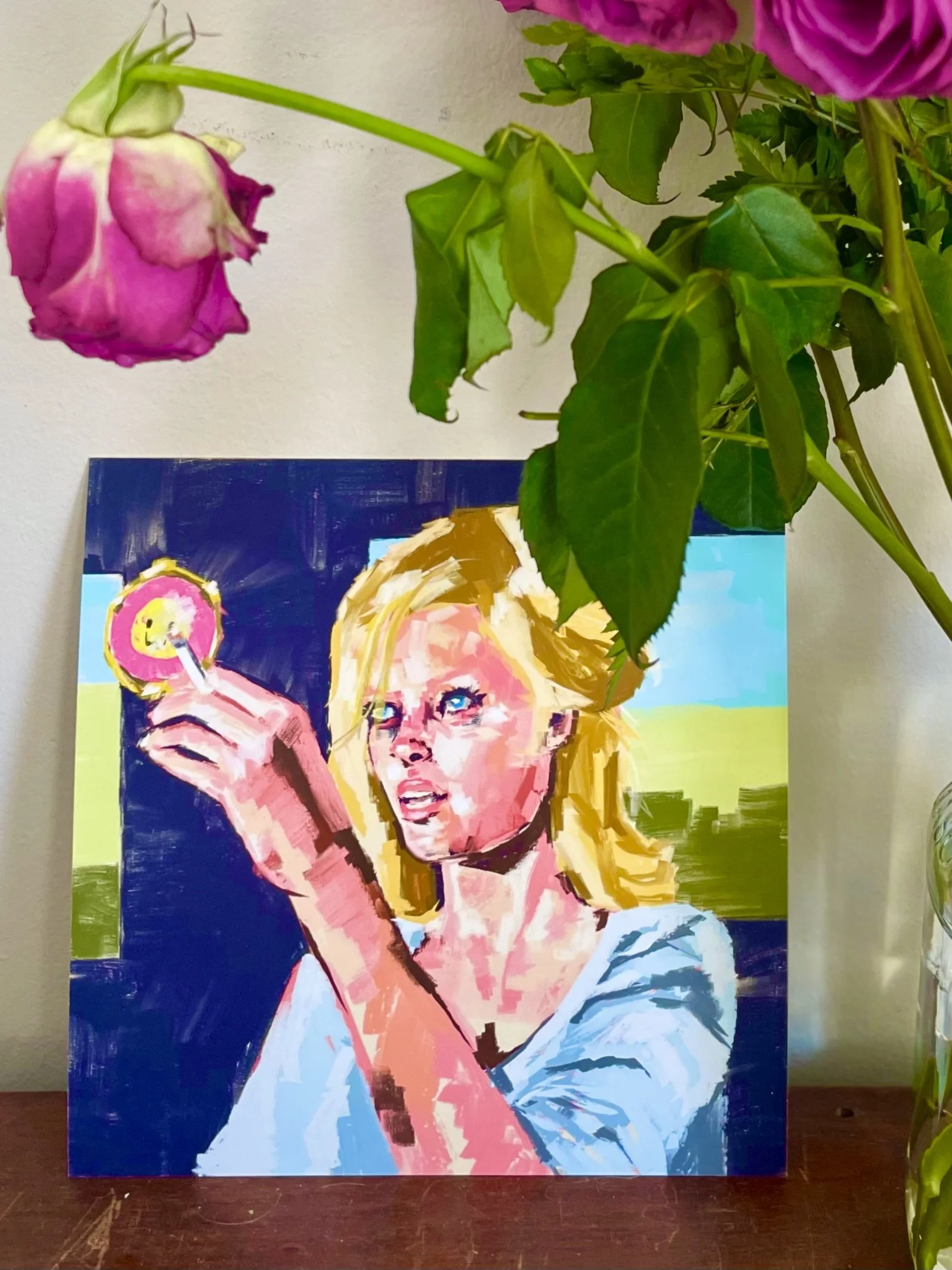 A colorful pop art style painting of a woman with blonde hair holding a yellow lollipop, set against a vibrant background with blue, green, and teal colors.