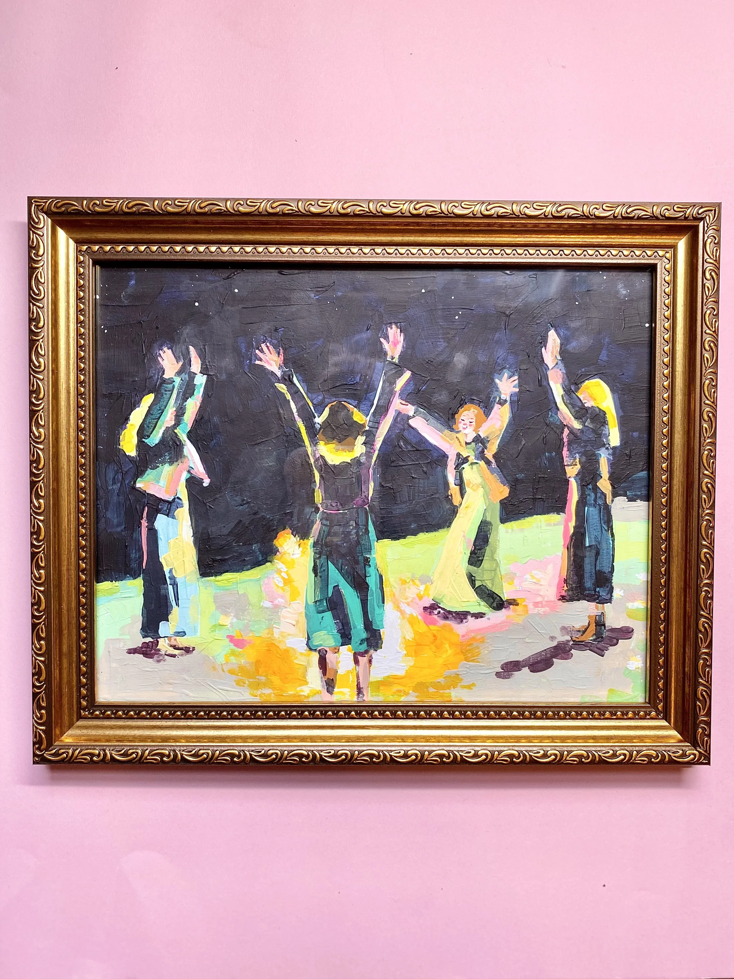 Colorful painting of children dancing or playing, framed in ornate gold, against a pink wall.