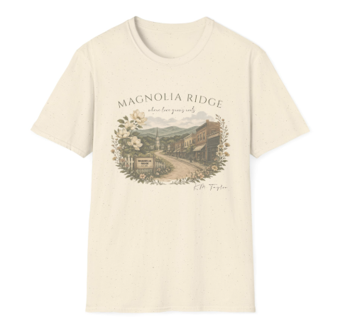 Cream-colored T-shirt with a graphic of a small town scene, including buildings and mountains, with the text 'Magnolia Ridge' above and a signature below.