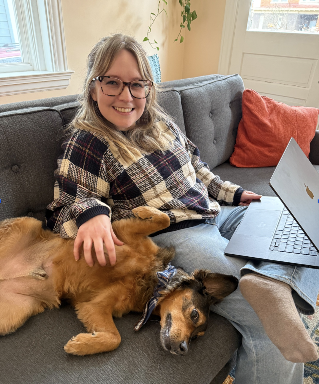 Kelsey, content strategist, working from couch with her dog laying next to her