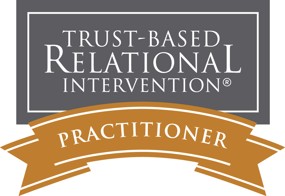 A badge with a dark gray background and white and brown accents that reads 'Trust-Based Relational Intervention Practitioner'.