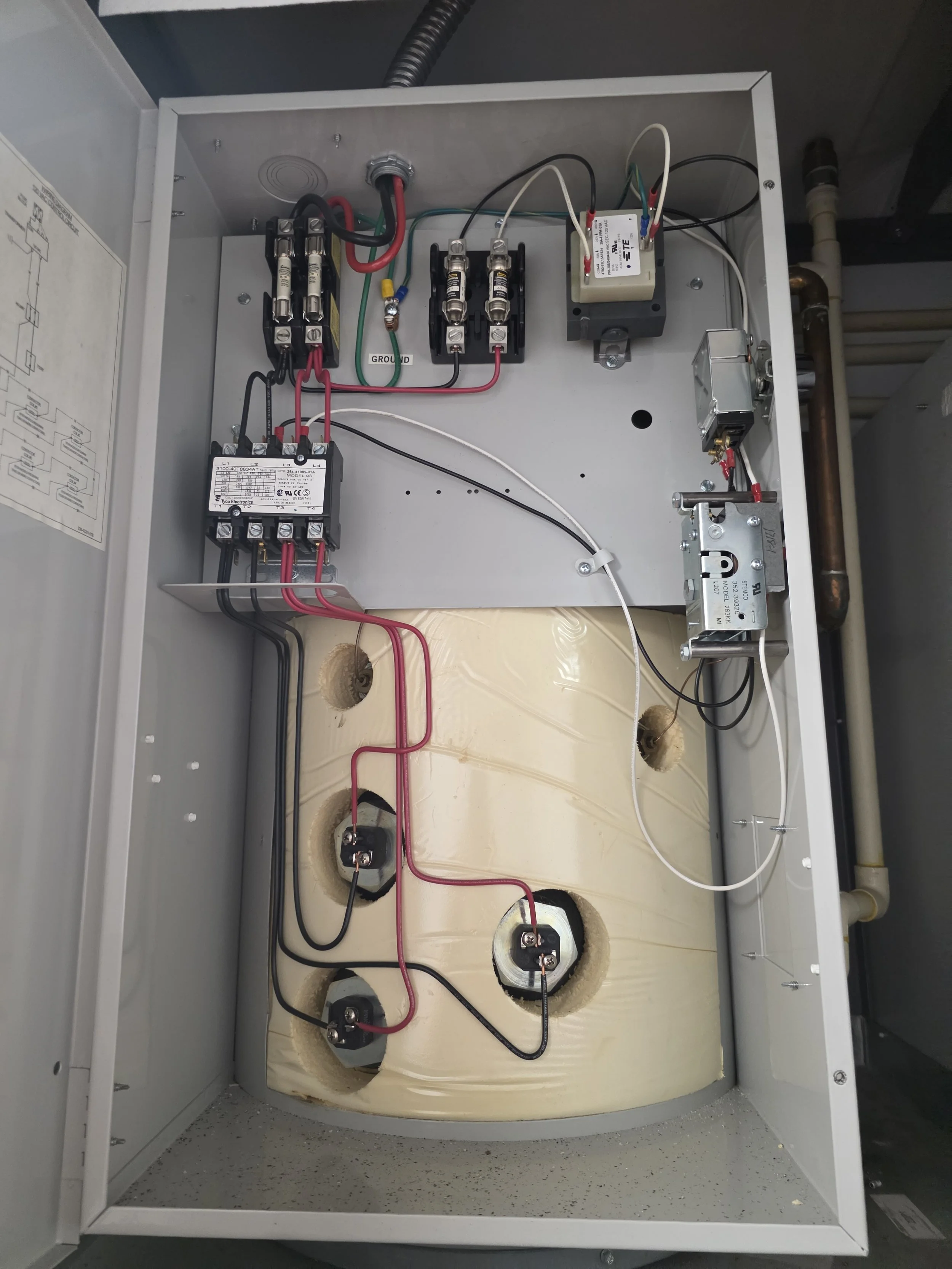 The inside of an electrical control panel with wires, relays, and connectors mounted on a metal enclosure