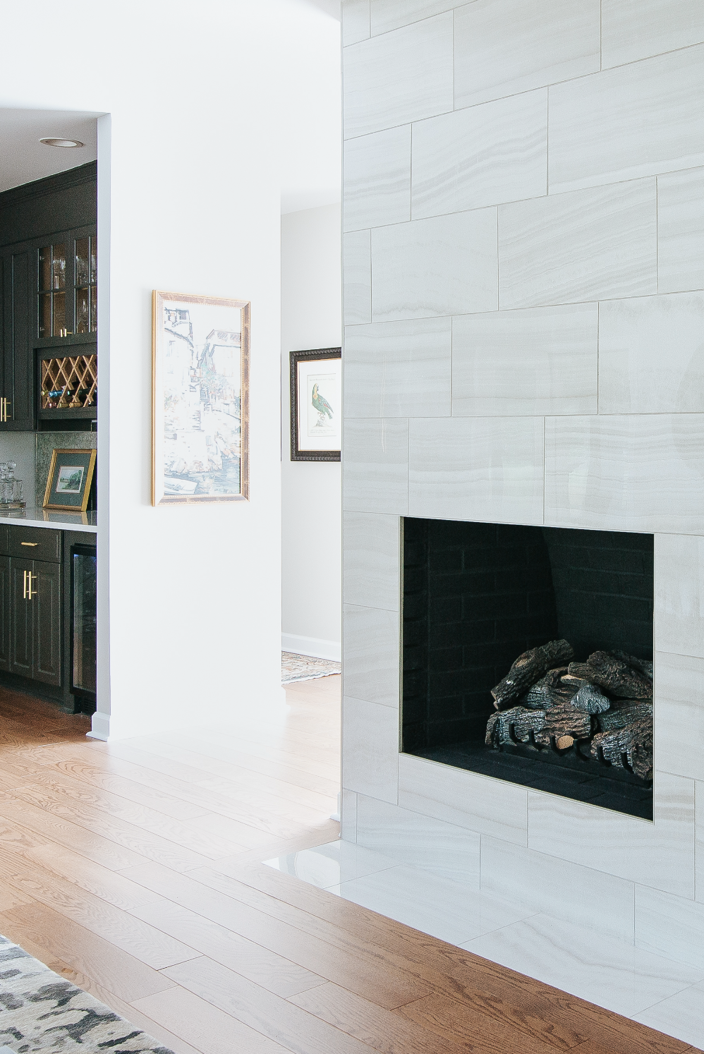 Modern living room featuring a white fireplace, light hardwood flooring, and moments of artwork on the walls.