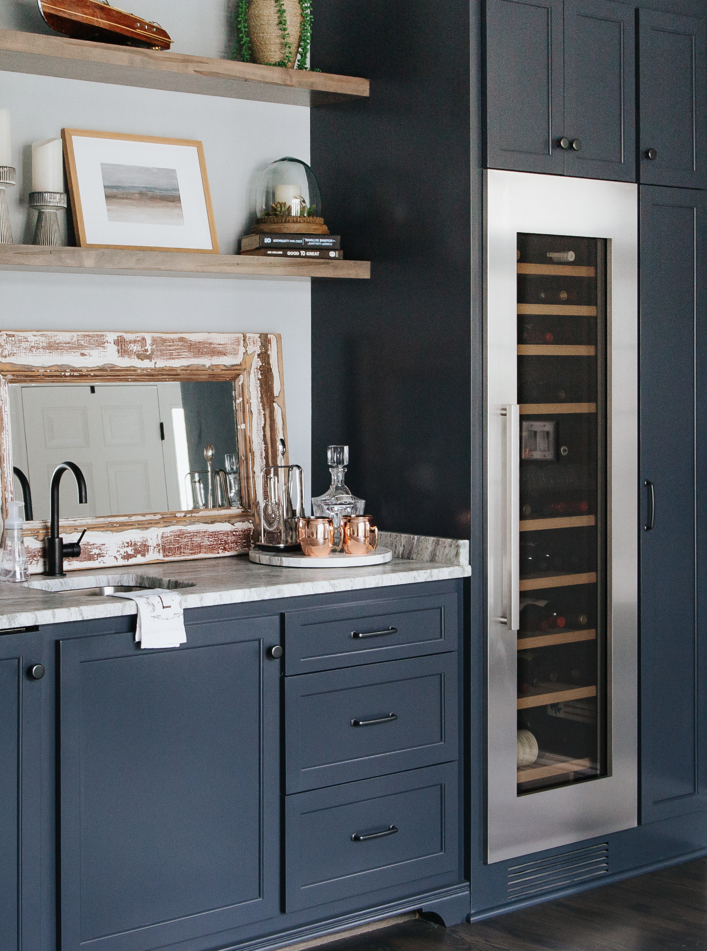 Kitchen bar with dark blue cabinets, white countertop, a wine cooler fridge, and a glass decanter set on a tray.