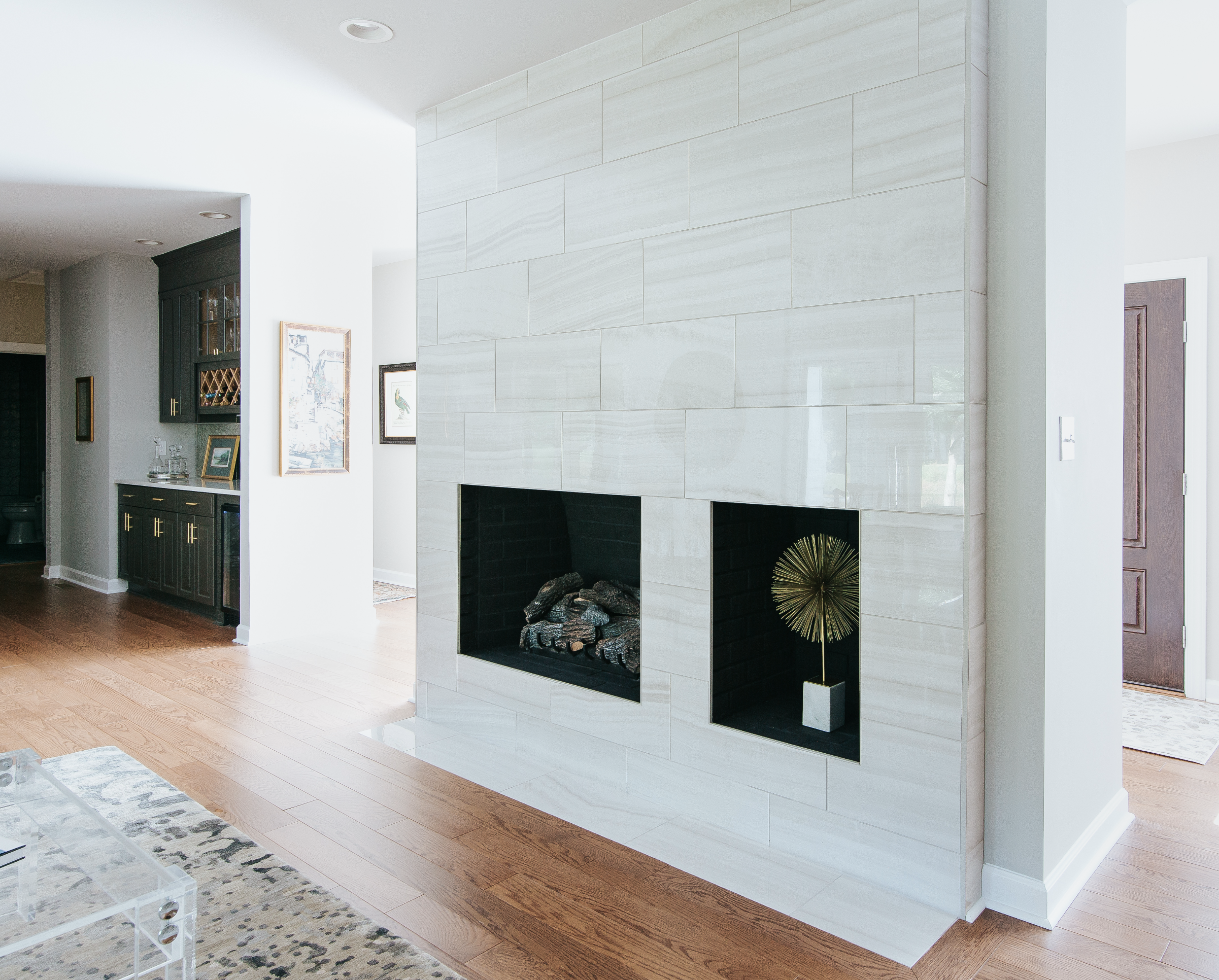 Living room interior with white marble fireplace, white walls and hardwood flooring.