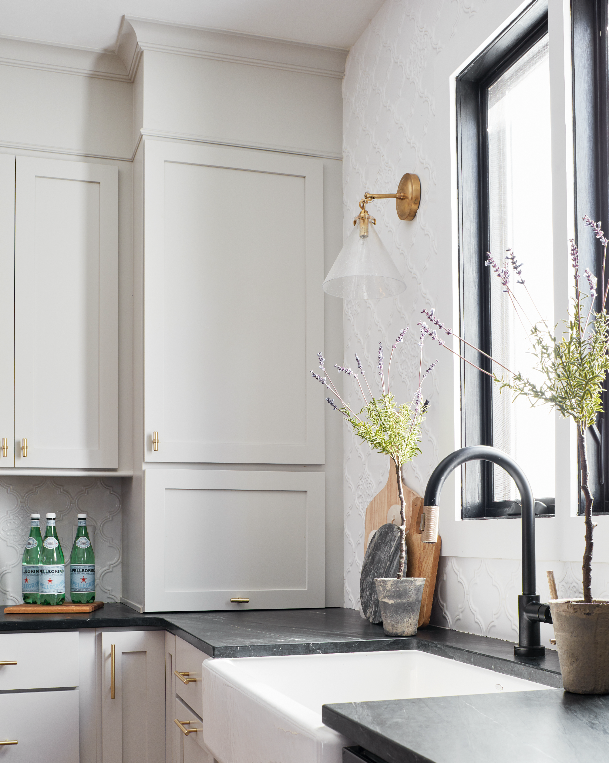 A contemporary kitchen with white cabinets, a black soapstone countertop and matte black faucet.