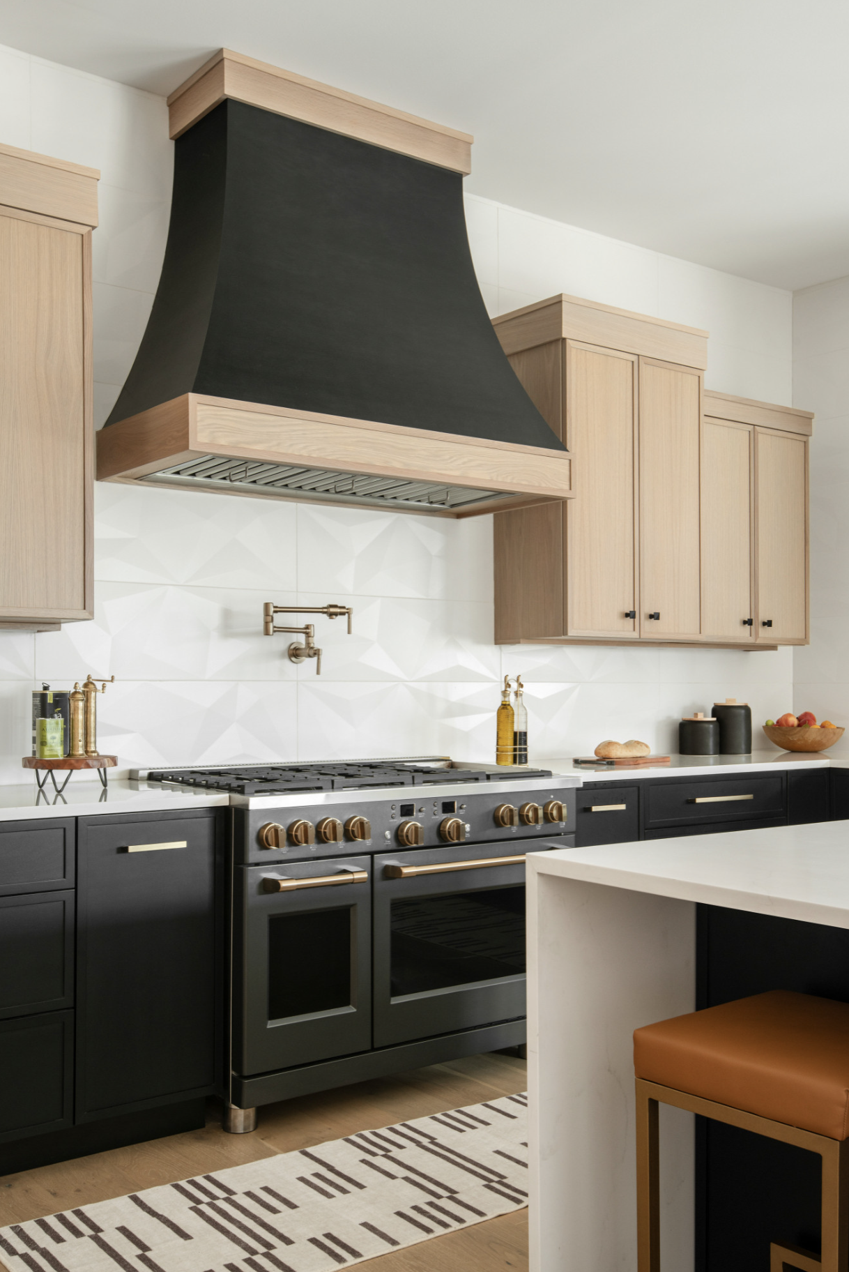 Contemporary kitchen with black and natural wood cabinetry, a stovetop with brass knobs, and a range hood with black and wood trim.