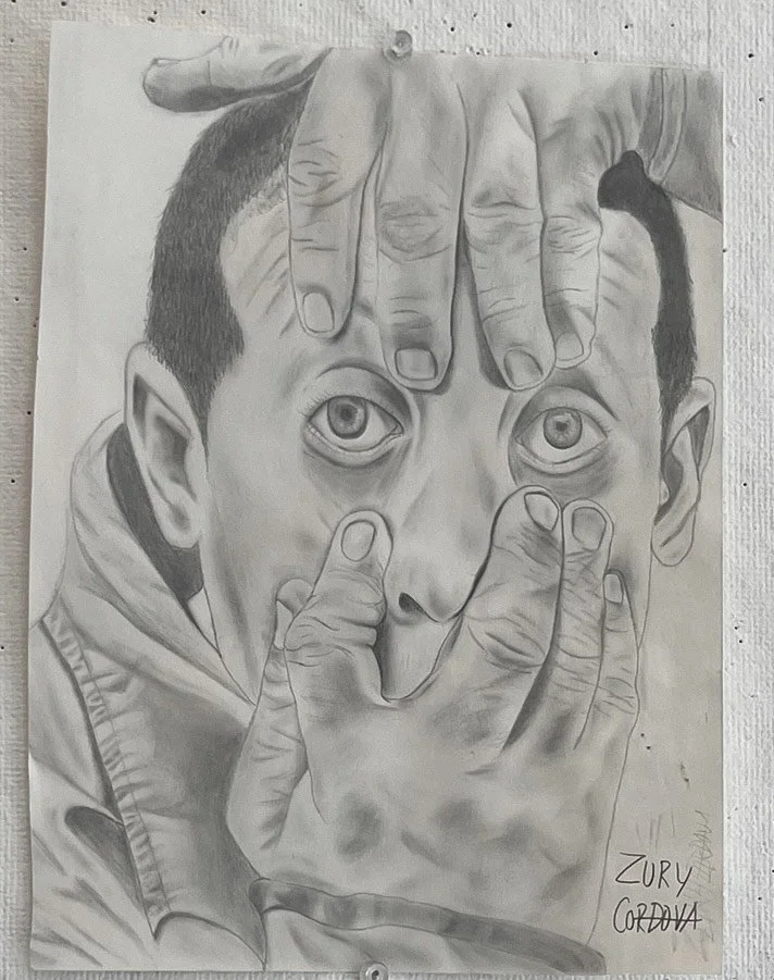A detailed black and white pencil drawing of a young man with short dark hair, holding his face with both hands, covering his forehead and mouth, revealing only his expressive eyes. The drawing is signed by the artist, Zury Cordova.