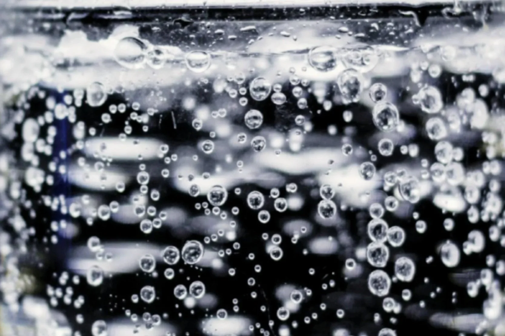 Close-up of bubbles in a dark soda or carbonated beverage.