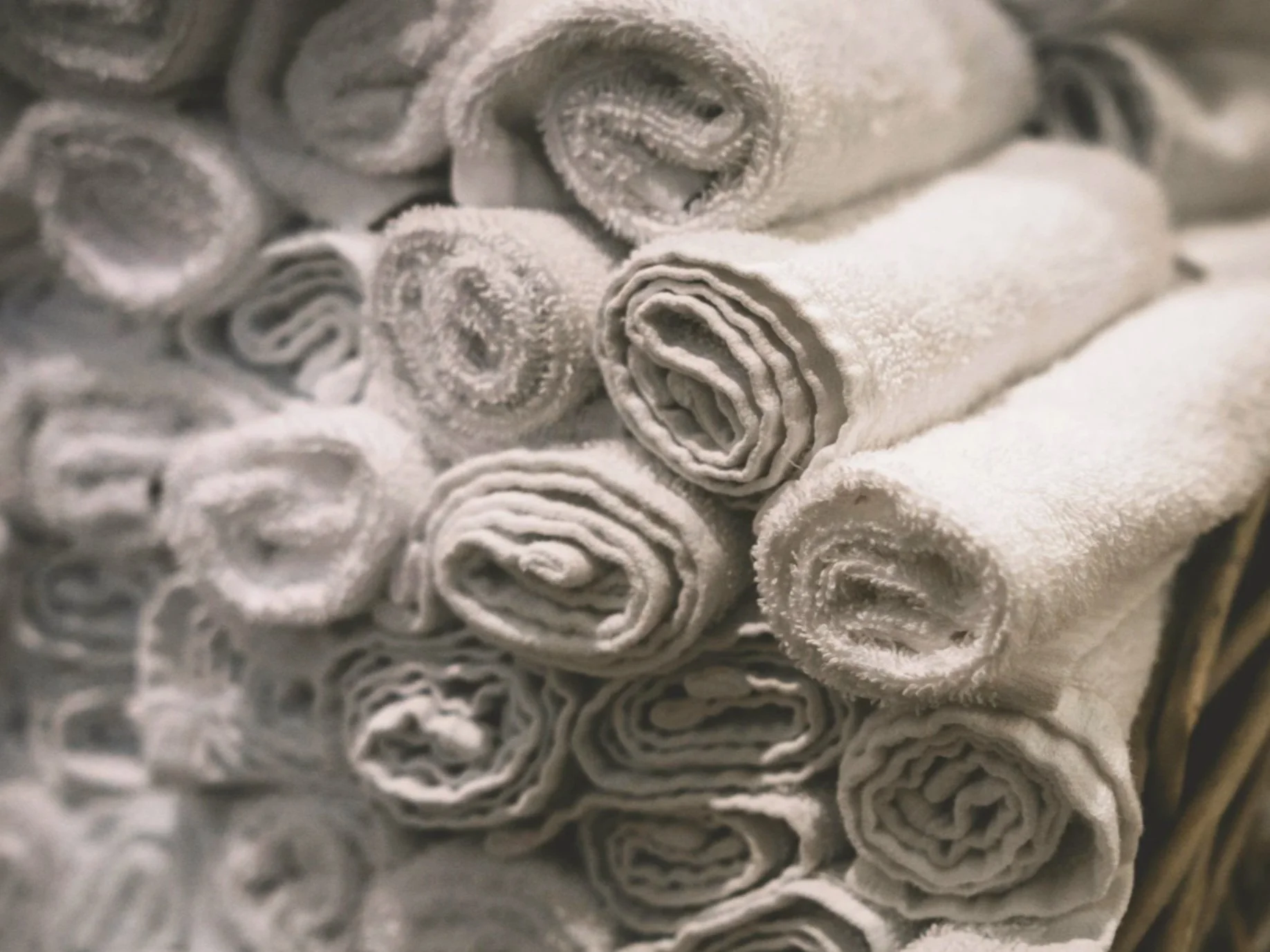 Close-up of rolled white towels stacked together.