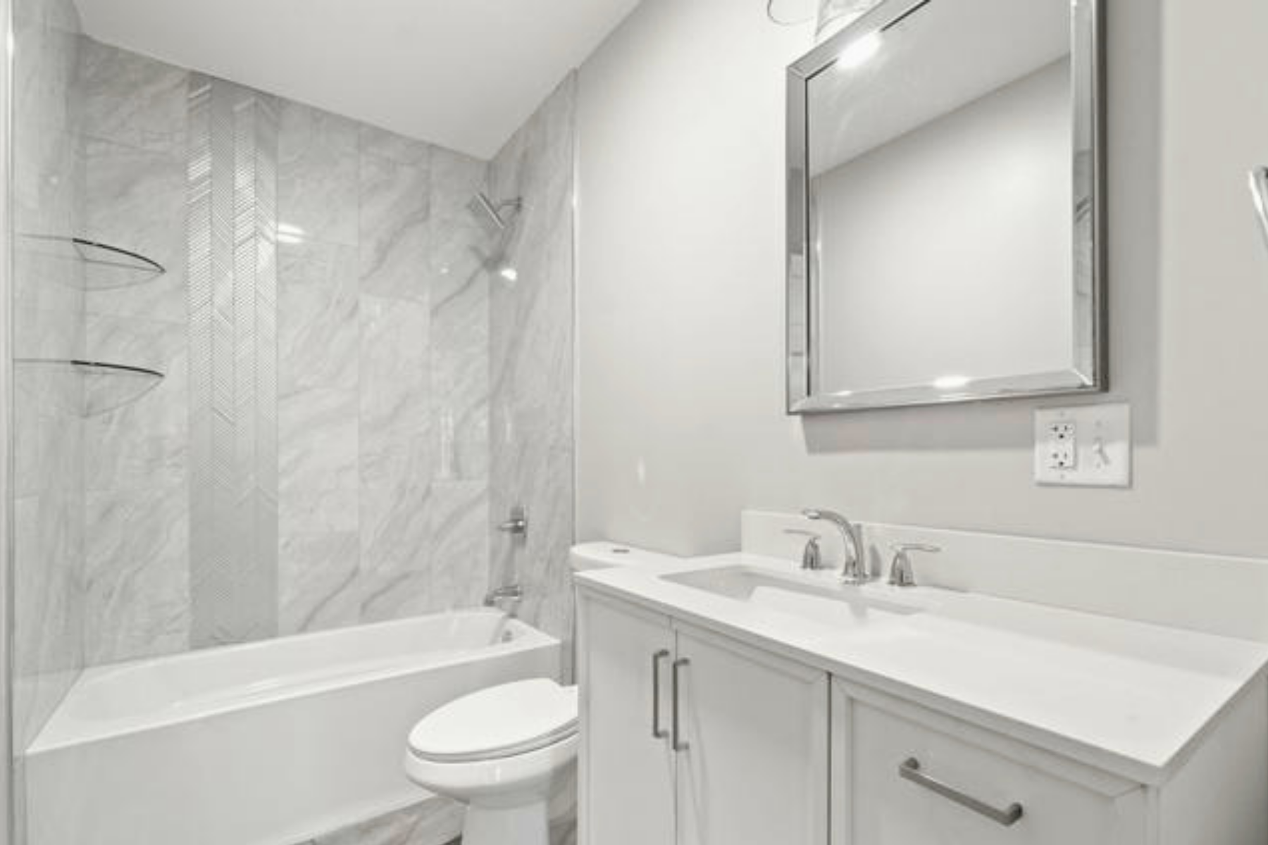 Modern bathroom with white vanity, double sink, large mirror, marble shower with built-in shelves, and toilet.