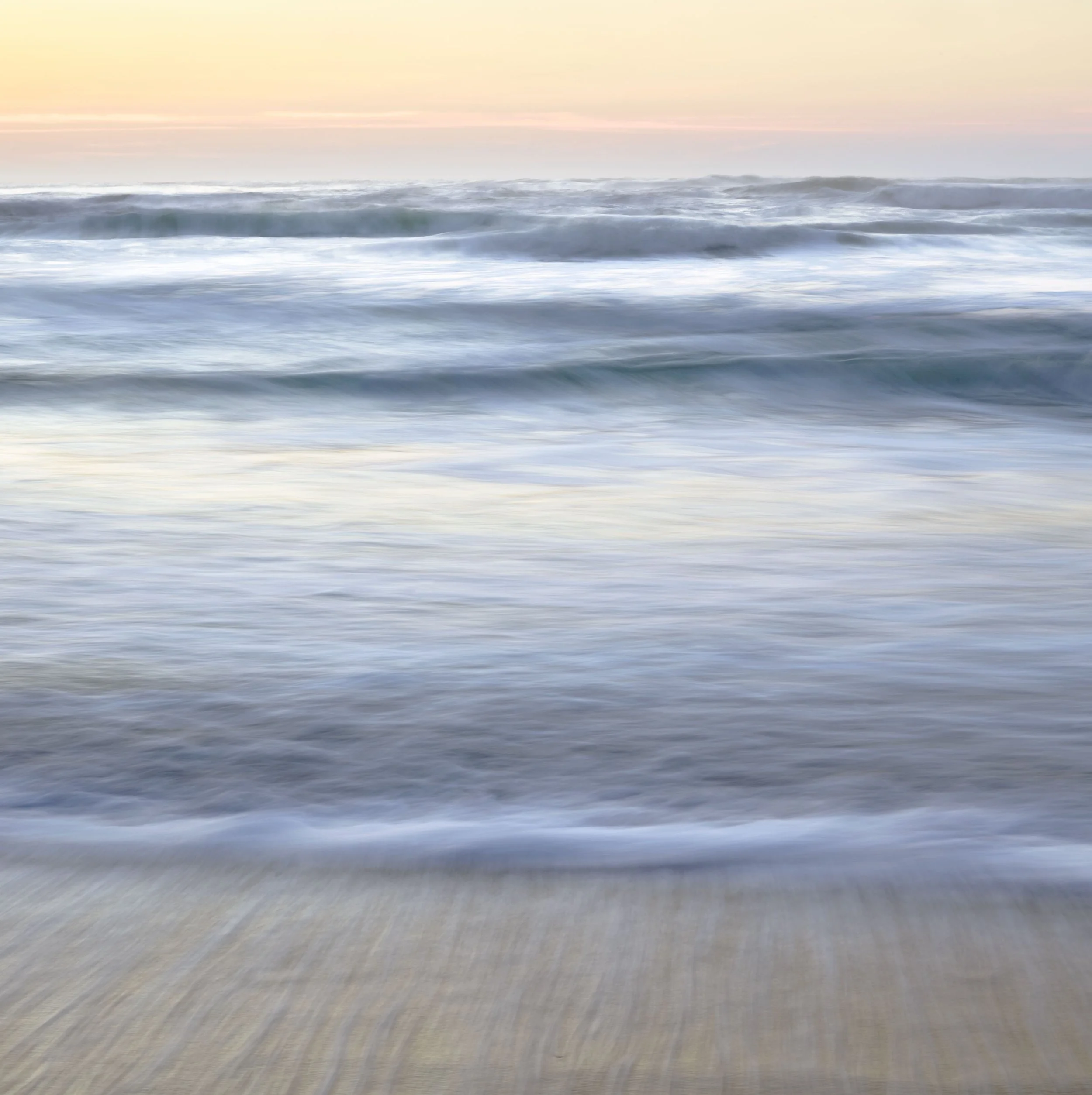 Vague image of the ocean with gentle waves and a pastel-colored sky.