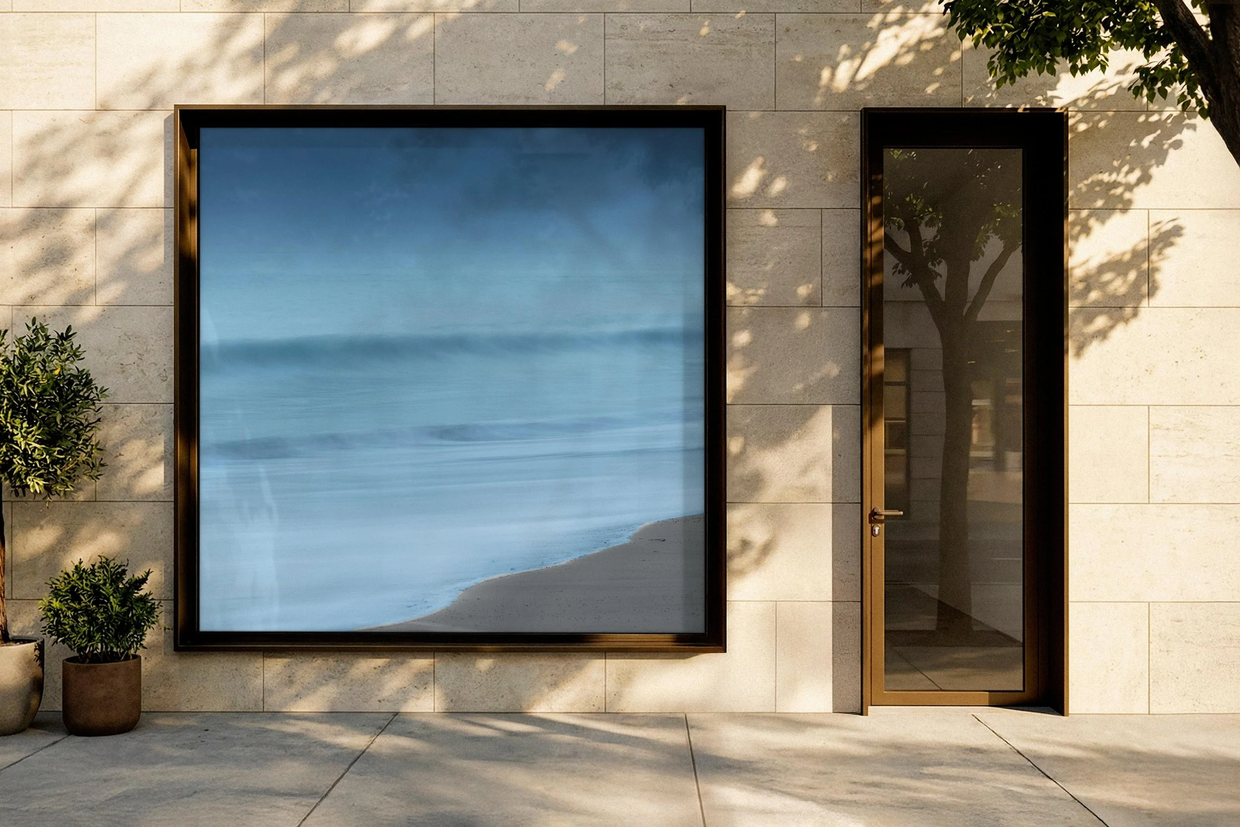 Vue d'une façade moderne avec un grand panneau en verre reflétant le ciel et un arbre, ainsi qu'une porte en verre avec cadre en métal, décoration minimaliste avec deux plantes en pot à gauche.