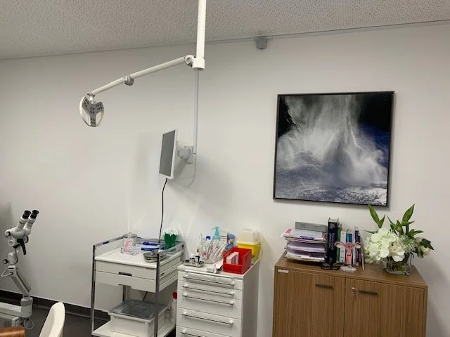 Salle de consultation dentaire ou médicale avec matériel, ordinateur, et décoration florale.