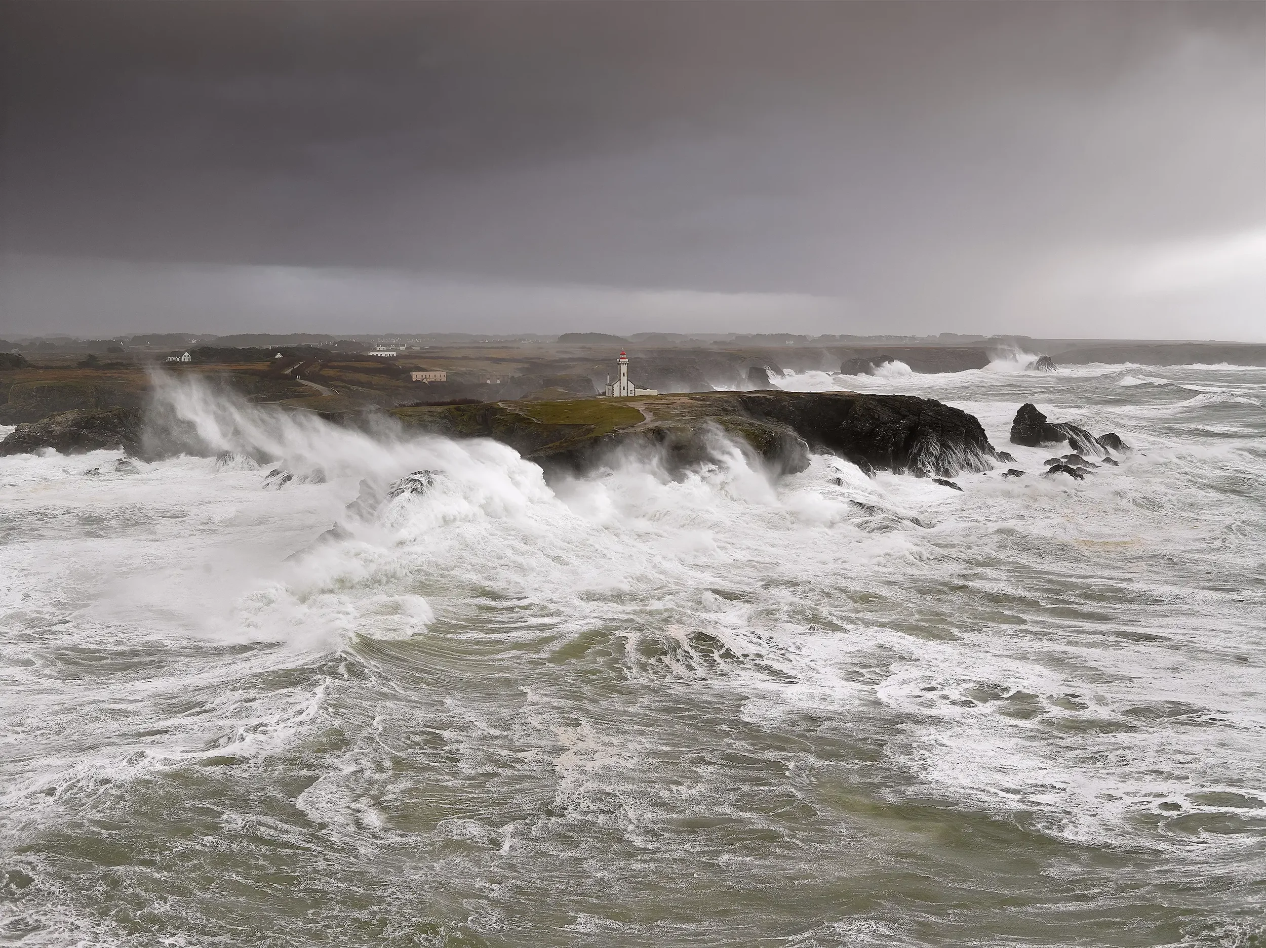 Pour une tempête, il y a beaucoup de vagues agitées et des nuages gris menaçants au-dessus de la côte.