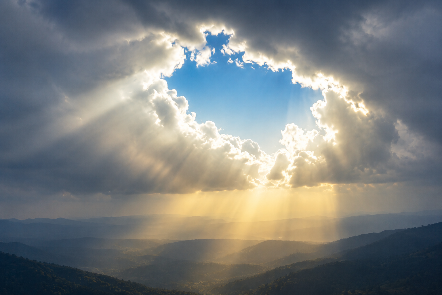 Sun rays breaking through clouds over a mountain landscape