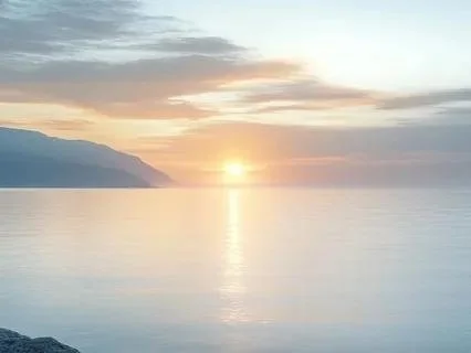 Sunset over a calm ocean with mountains in the background