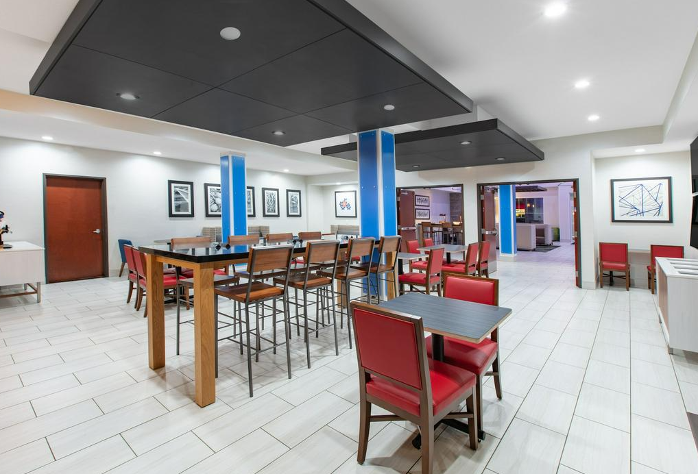 Interior of a modern restaurant or lounge with tables, chairs, and artwork on the walls.