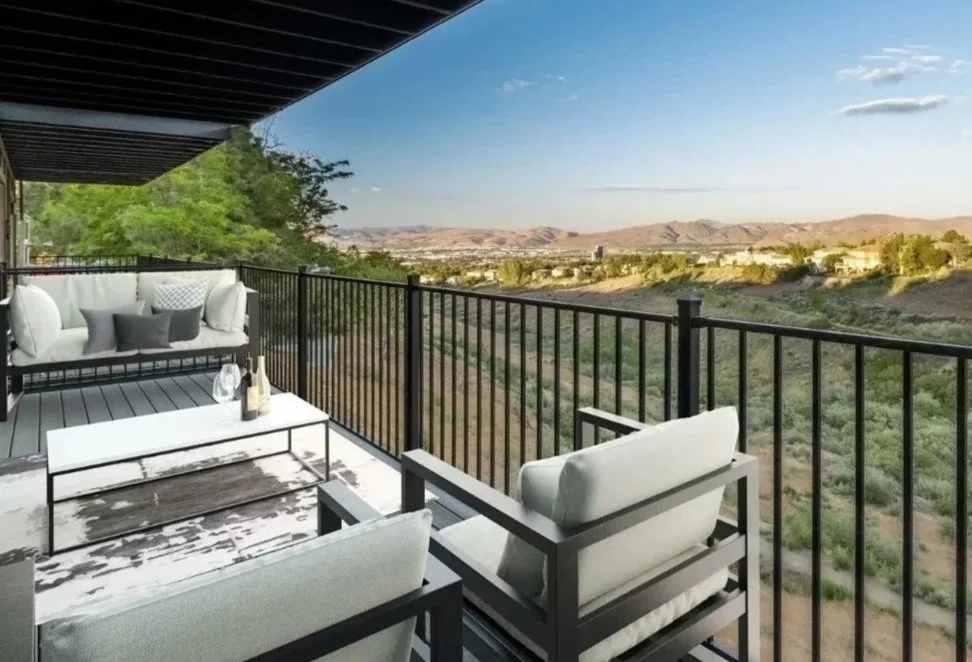 Outdoor balcony with seating area and scenic view of desert landscape and hills in the distance.