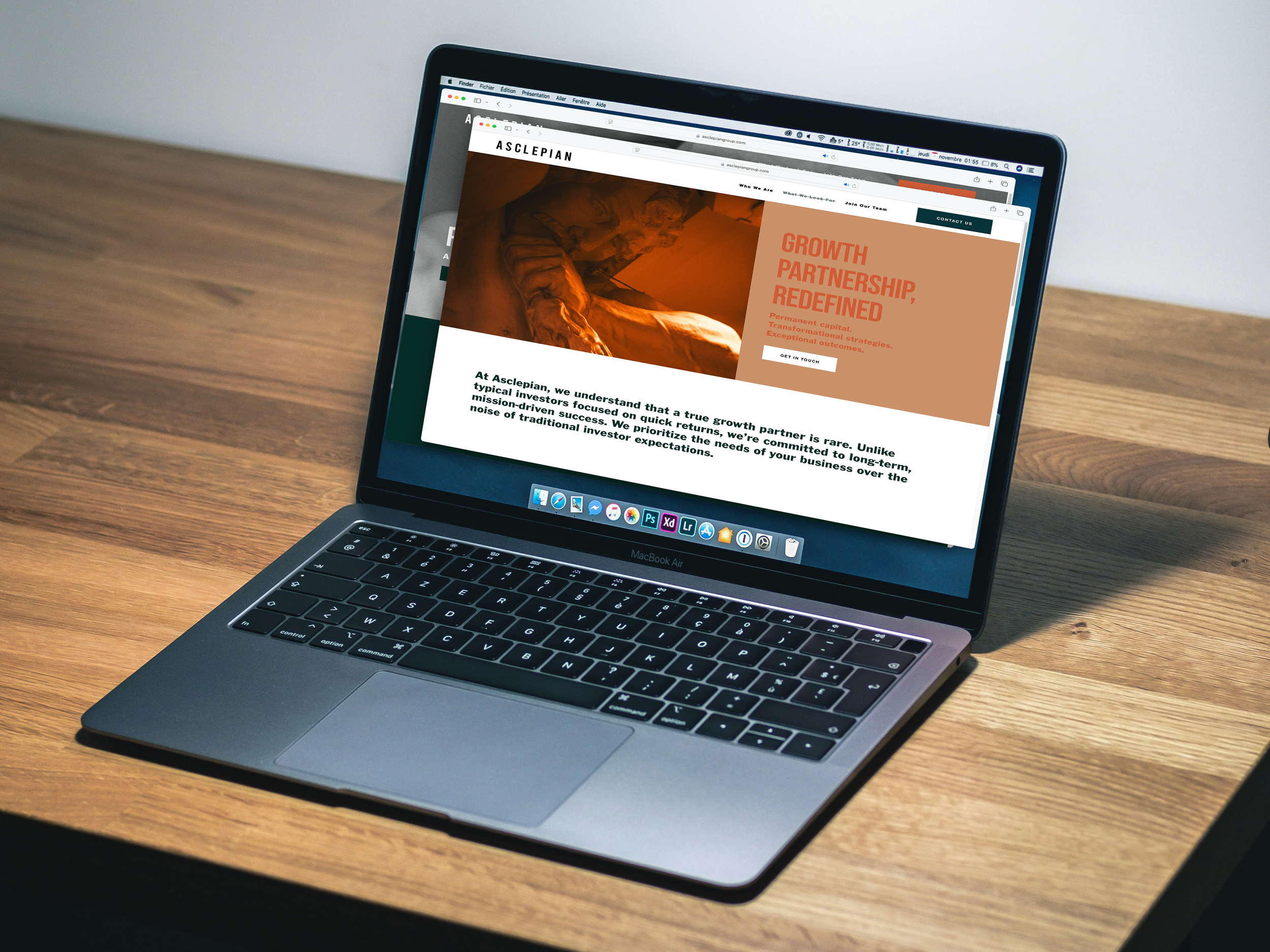 A MacBook Air laptop on a wooden desk displaying a website for Asclepian, focusing on growth, partnership, and redefined success.