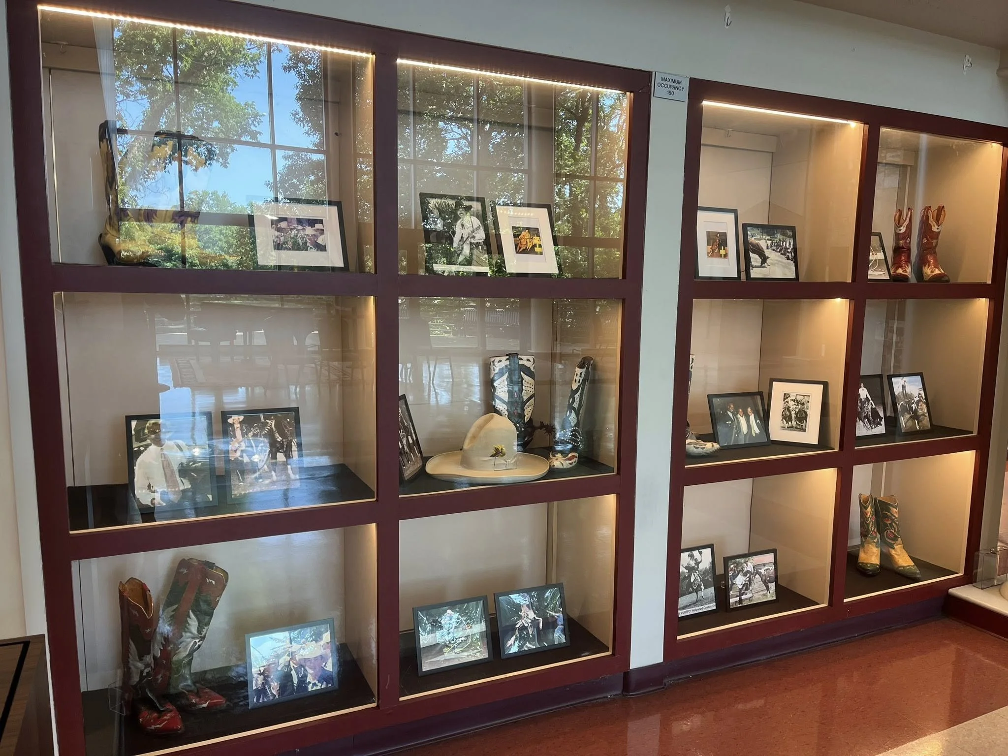Display case with framed photographs, cowboy boots, and western-themed items.