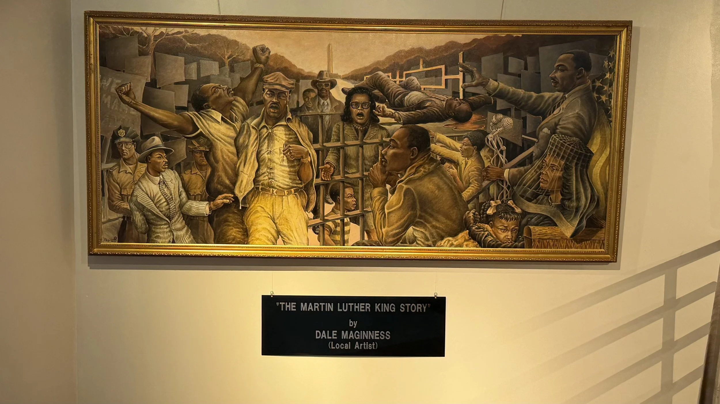 A mural depicting Martin Luther King Jr. giving a speech, surrounded by various people, including women and men, in a historical setting with the Washington Monument in the background.