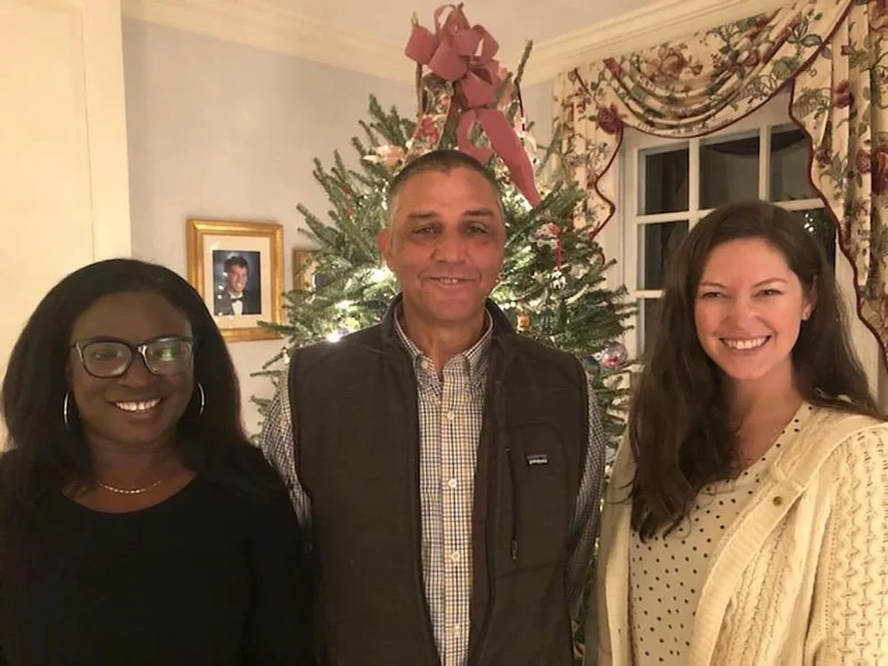 Photo of founding leaders, three people smiling in front of a decorated Christmas tree in a living room.