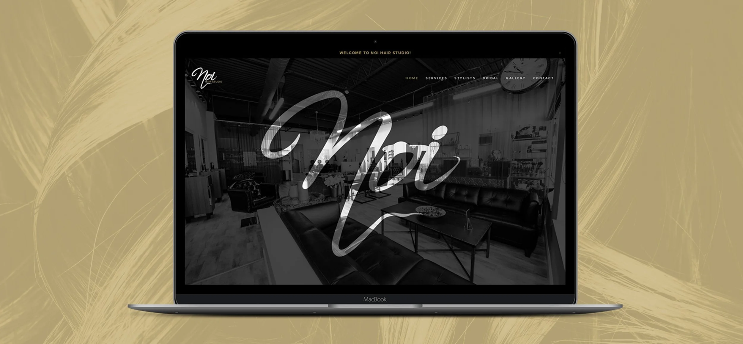 A MacBook laptop displays a black and white image of a modern salon interior with the word 'Noi' written in large cursive across the screen, with a golden decorative background.