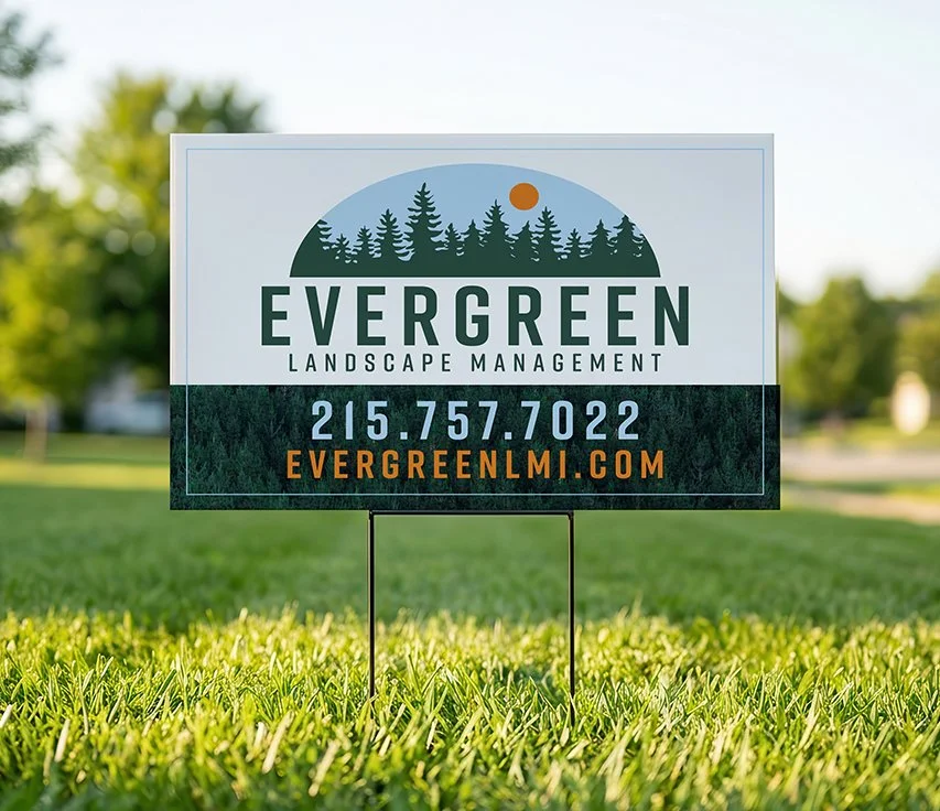 Sign for Evergreen Landscape Management on grass with trees and sky in background.