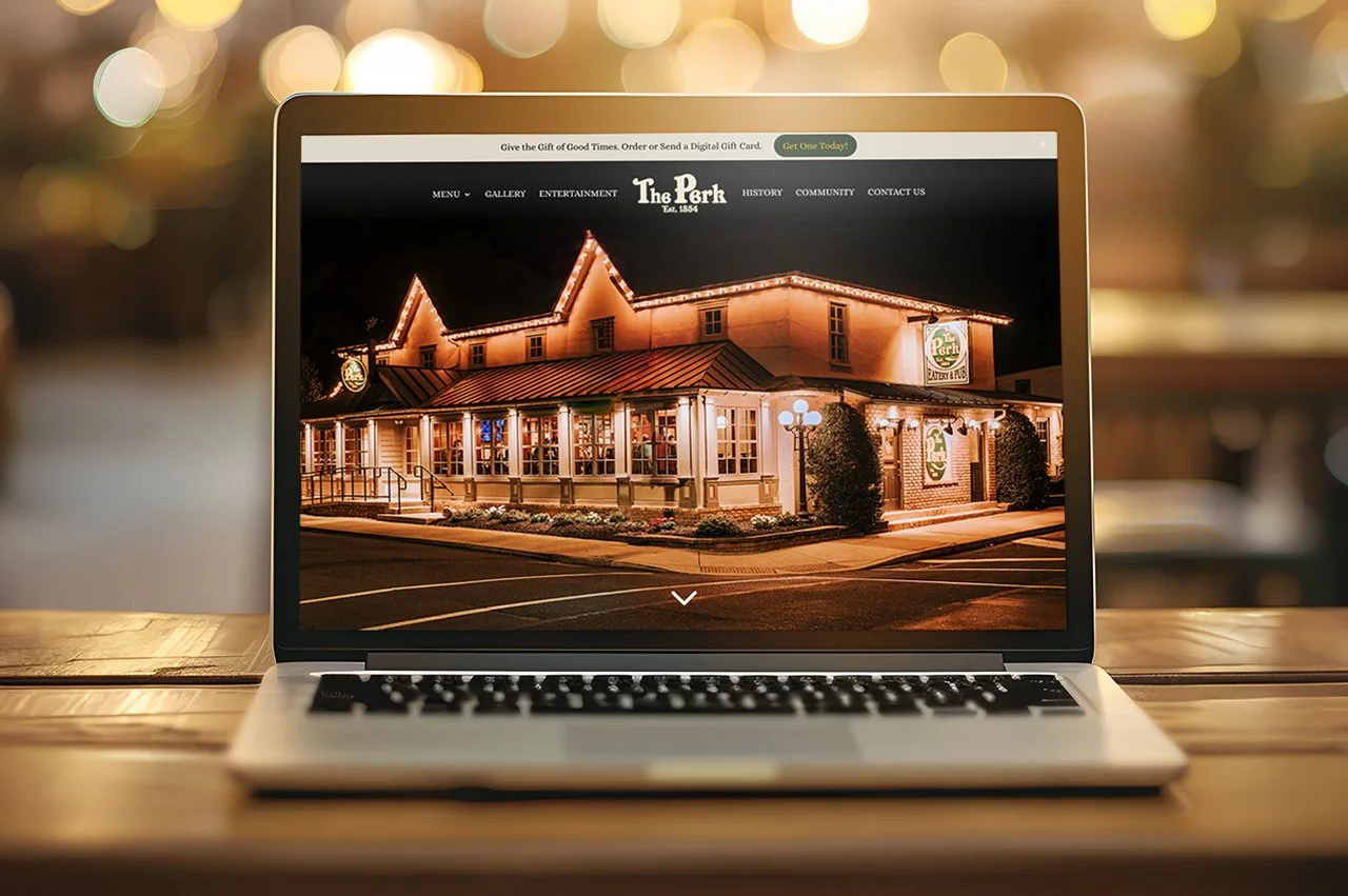 Laptop displaying 'The Park' restaurant website, showcasing an outdoor evening patio layout.