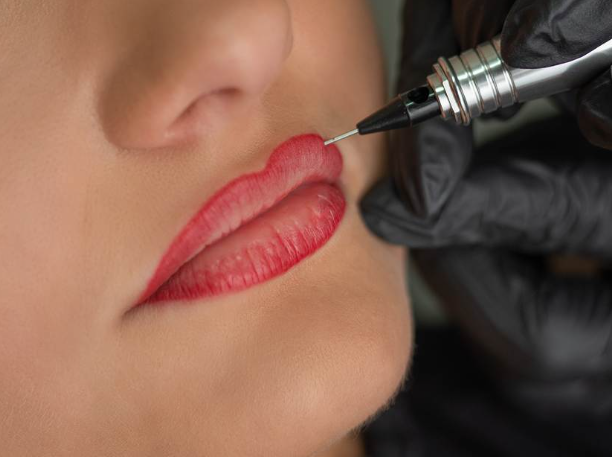 Pessoa recebendo procedimento de tatuagem ou preenchimento labial com uma seringa por profissional de luvas pretas.