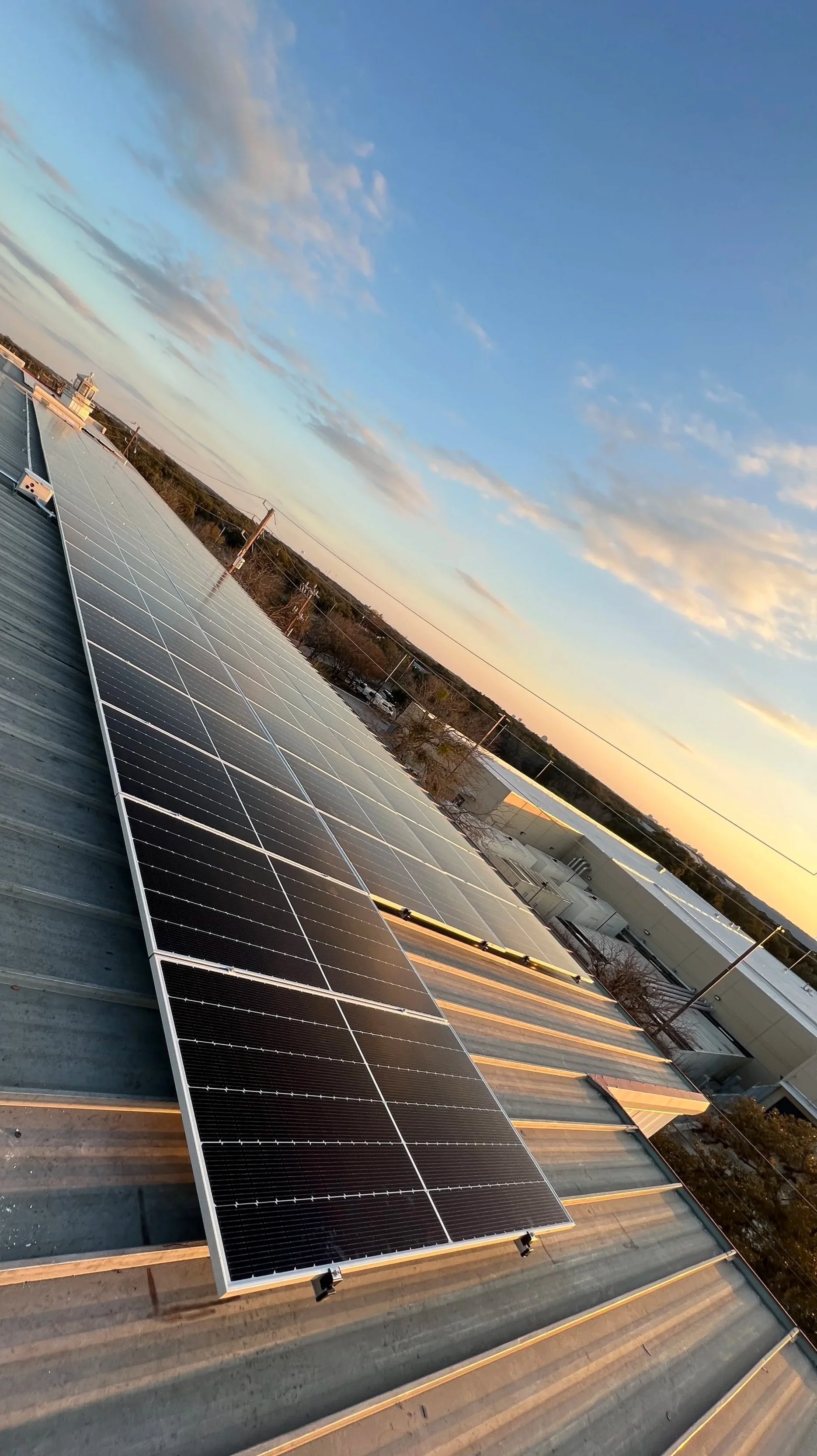 Solar panels installed on a rooftop with a clear sky background and some clouds.