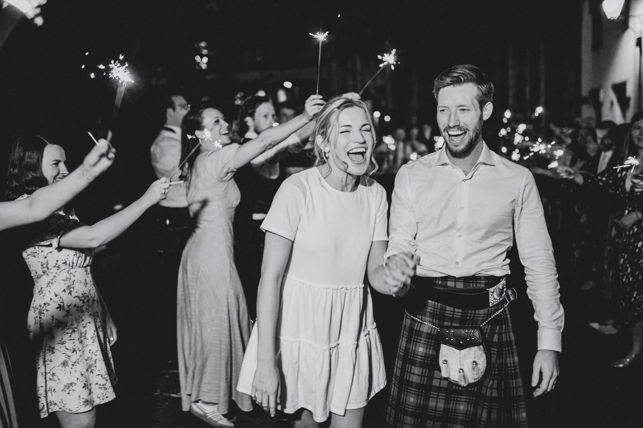 People celebrating with sparklers at night, smiling and enjoying a festive event.