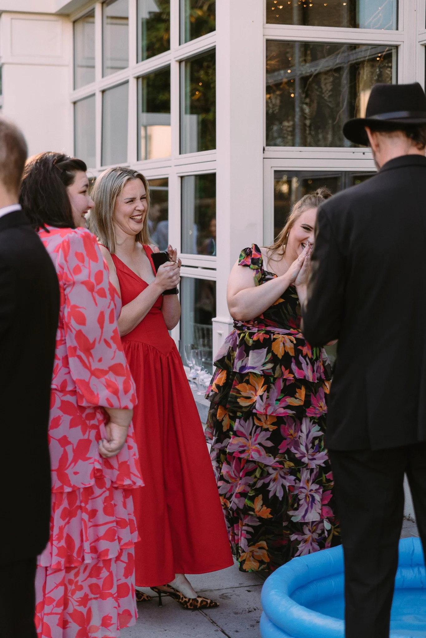 Group of women dressed in colorful dresses engaging in conversation at an outdoor social gathering.