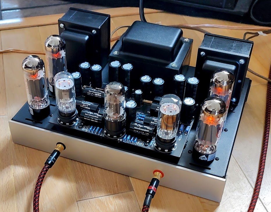 A tube amplifier with vacuum tubes and transformers on a wooden surface.