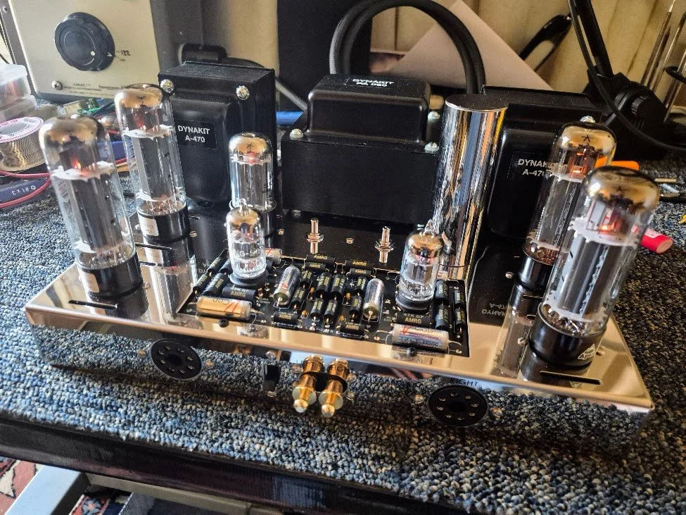 A vintage tube amplifier with vacuum tubes, transformers, and electronic components on a textured surface.