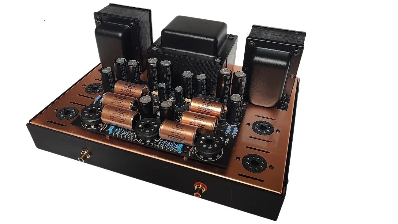 A vintage-style electronic device with large copper-colored capacitors, black transformers, and various circuit components on a copper-colored metal base.