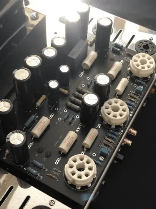 Close-up of a vintage electronic audio or radio equipment circuit board with capacitors, resistors, and vacuum tubes.