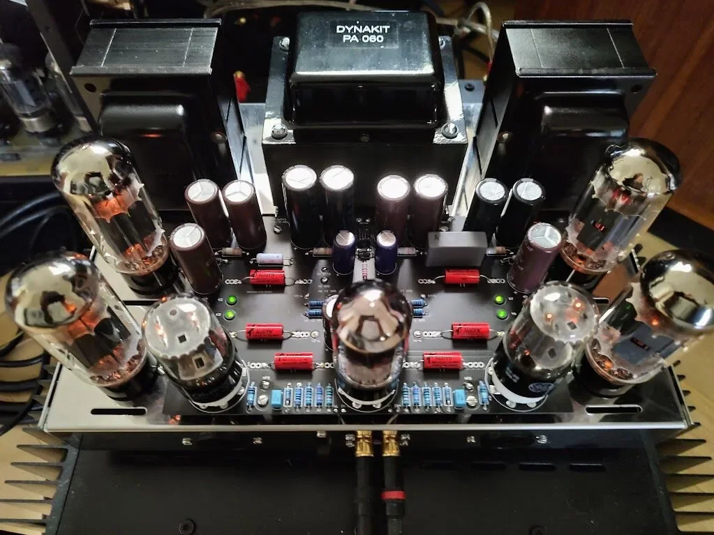 A close-up view of a vintage audio amplifier with vacuum tubes, capacitors, and various electronic components on a circuit board.
